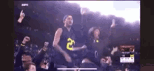 a group of people are watching a basketball game and one of them is wearing a number 2 jersey .