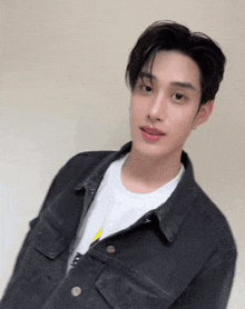 a young man is wearing a black denim jacket and a white shirt .