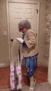 an elderly woman in a costume is standing next to a pink suitcase