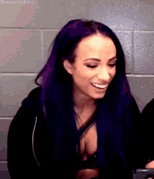 a woman with purple hair is smiling for the camera