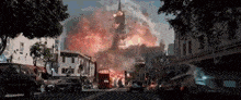 a large explosion is taking place in a city with cars driving down the street .
