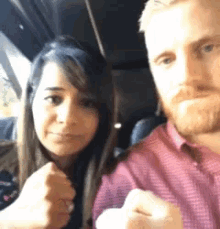 a man and a woman are posing for a picture and the woman is wearing a ring