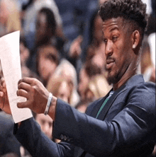 a man in a suit holds a piece of paper in his hand