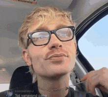 a man wearing glasses and a choker is sitting in the back seat of a car