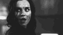 a black and white photo of a woman 's face with blood on it .