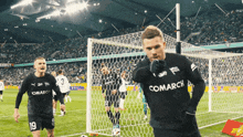 a soccer player wearing a black jersey with the word comarch on the back