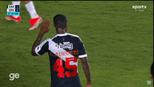 a soccer player wearing a shirt that says betfair points at the referee
