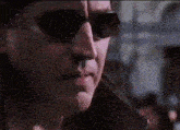 a close up of a man 's face wearing sunglasses and a black jacket .