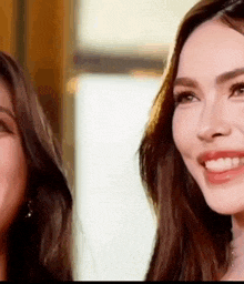 two women are smiling and looking at each other in a blurry photo .