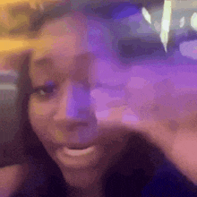 a woman is making a funny face in front of a purple light .