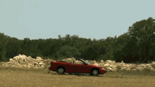 a red convertible car is parked on the side of the road