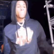 a man in a blue hoodie is standing in front of a microphone and making a funny face .