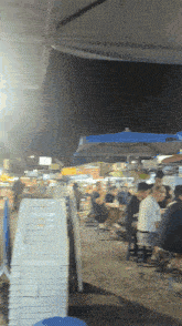 a group of people sit at tables under umbrellas