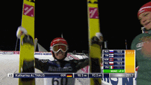 a person holding skis in front of a screen that says katharina althaus on it