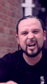 a man with dreadlocks and a beard is making a funny face with his mouth open