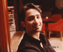 a man in a black shirt is smiling and the word toree is on the bottom