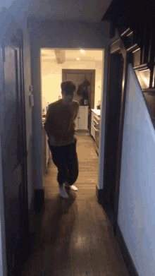 a man in a yellow sweater is walking down a hallway in a kitchen