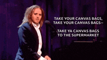 a man in a suit stands in front of a microphone with the words take your canvas bags