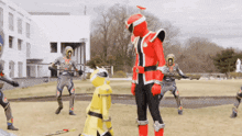 a group of superheros are standing in a field and one of them is wearing a red costume