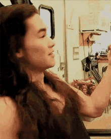 a man with long hair is taking a picture of himself with his phone .