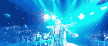 a man is standing on a stage with his arms outstretched .
