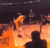 a basketball player is dribbling the ball on a court while another player tries to block him .