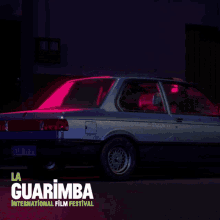 a poster for la guarimba international film festival with a car in the background