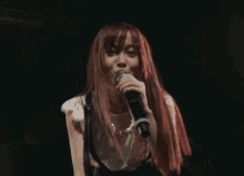 a woman with red hair is singing into a microphone with her mouth open