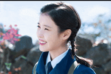 a young woman wearing a blue jacket and tie smiles for the camera