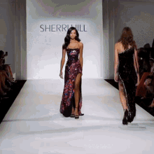 two models walk down the runway at a sherri hill show