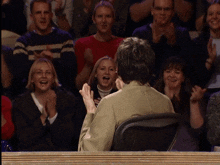 a man sitting in front of a crowd clapping
