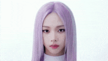 a woman with purple hair is standing in front of a white background and looking at the camera .