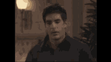 a man in a black shirt is standing in front of a lamp in a living room .