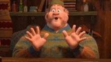 a man in a sweater is sitting at a table with his hands outstretched .