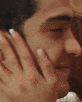 a close up of a man 's face with a woman 's hand covering his ear .