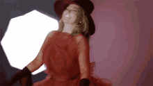 a woman in a red dress and hat is dancing with her arms outstretched