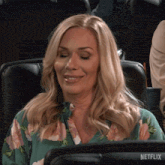 a woman in a green floral shirt is sitting in a netflix seat