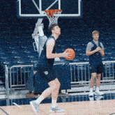 a man holding a basketball on a court in front of a net