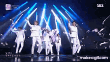 a group of young men are dancing on a stage with sbs written on the bottom