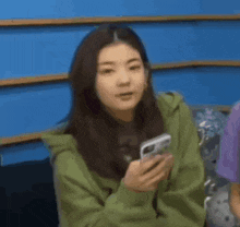 a woman is sitting on a couch holding a cell phone .