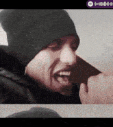 a man wearing a black beanie is making a face