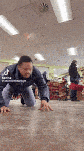 a man is crawling on the floor in a store with tiktok written on the bottom