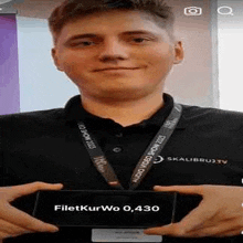 a young man in a black shirt and lanyard is holding a box .
