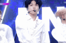 a man wearing a white shirt and a microphone stands in front of a large letter n