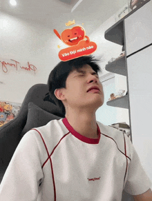 a man sitting in a chair with a sticker on his head that says " vào doi mình não "