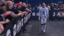 a man in a denim jacket is walking through a crowd of people in a stadium .