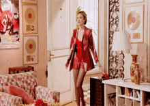 a woman in a red jacket and shorts is walking in a living room
