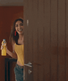 a woman in a yellow top is holding a bottle of juice