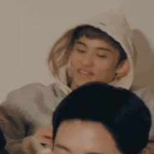 a man in a hoodie is sitting next to a woman in a room .