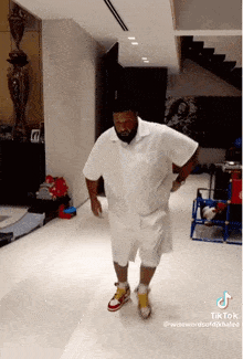 a man in a white shirt and shorts is dancing in a living room .